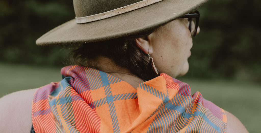 Person wearing an orange plaid scarf and hat outdoors