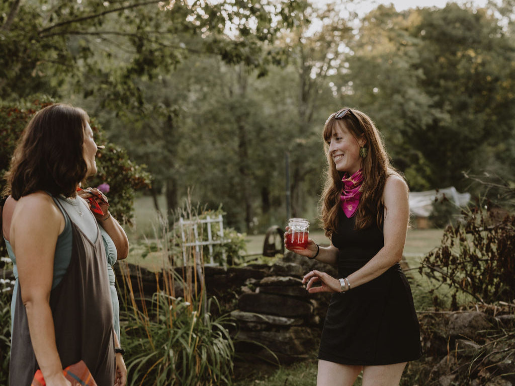 Two women standing outdoors in a garden setting, engaged in conversation.